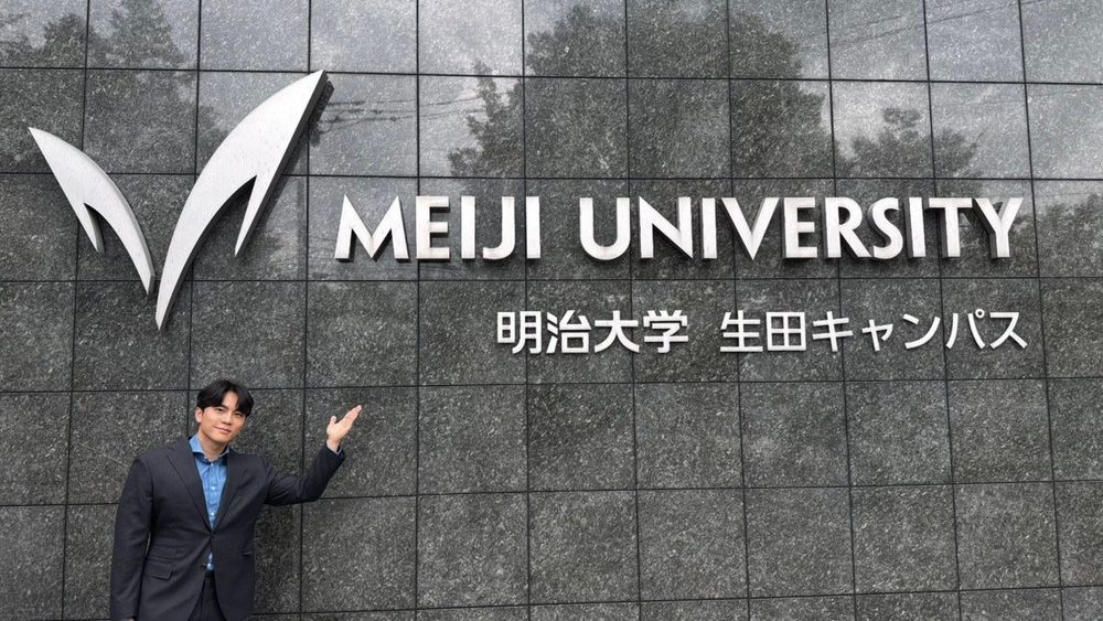 明治大学生田キャンパスの看板前に立つスンジュン